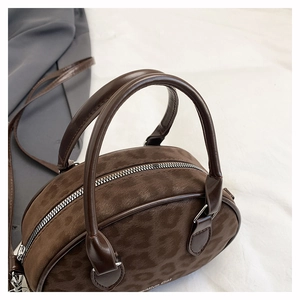 Detailed view of brown leopard print suede texture and silver zipper on the handbag