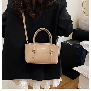 Détail du sac à main beige avec poignée en cuir noué et accents métalliques argentés