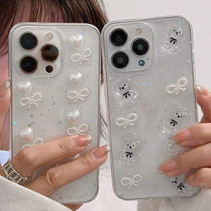 Gros plan d'une coque iPhone pailletée avec perles blanches, cœurs et petit ours en 3D