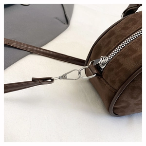 Detail of dark brown suede bag with silver metal zipper and leather shoulder strap