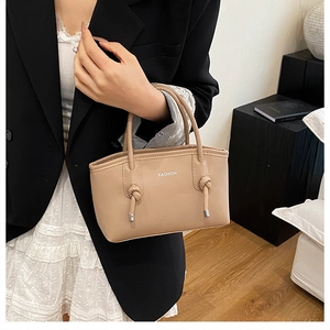 Détail d'un sac cabas en cuir beige avec texte Fashion porté par une femme