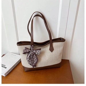 Detailaufnahme der Canvas-Tasche mit Lederbesatz und elegantem Seidenschal-Accessoire