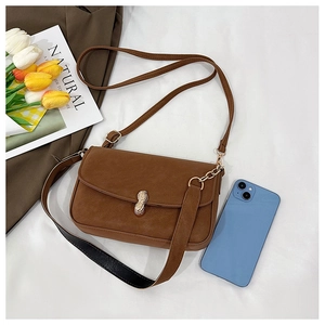 Detailed view of a brown faux leather baguette bag featuring a gold peanut-shaped buckle