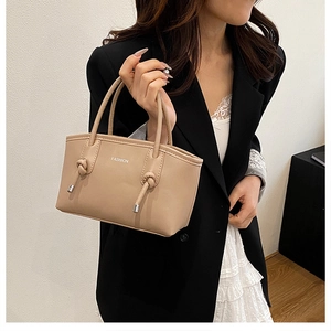 Détail du sac à bandoulière abricot avec nœud sur l'anse et texte Fashion imprimé