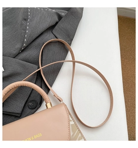 Detailed close-up of beige crossbody bag with FASHION & BAGS lettering and textures