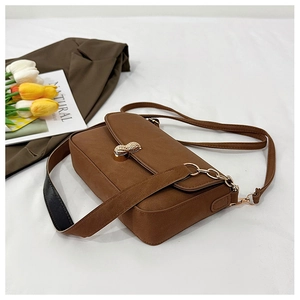 Detail of caramel brown bag featuring a unique golden peanut-shaped metal twist lock closure