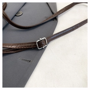Close-up of adjustable brown leather shoulder strap with silver buckle on suit
