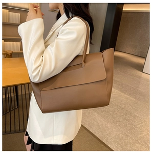 Detailed view of brown leather tote bag showing magnetic flap closure and long shoulder strap