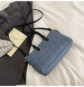 Close-up of blue denim and black leather crossbody bag with elegant gold hardware details