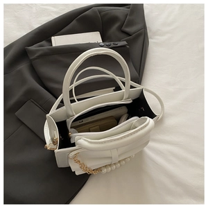 Gros plan de l'intérieur du sac à bandoulière en cuir blanc montrant un large rangement
