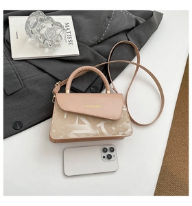 Close-up of beige crossbody bag with fashion lettering and asymmetrical flap design