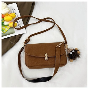 Detail of vintage brown shoulder bag with golden peanut buckle and fuzzy charm