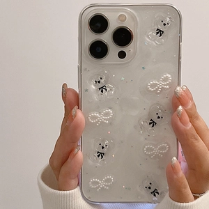 Détail d'une coque iPhone à paillettes avec oursons 3D et nœuds perles en main