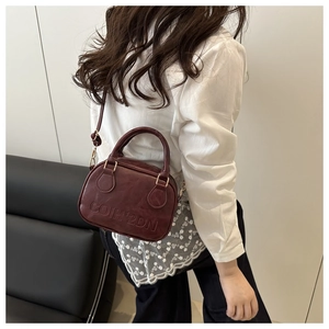Detail view of burgundy PU leather mini handbag with embossed letters and gold hardware