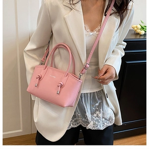 Mannequin portant un sac à bandoulière rose clair avec logo et détails de glands