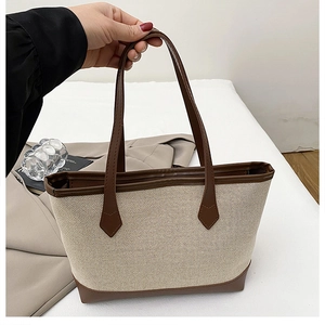 Detail of canvas tote with brown leather handles and drop-shaped stitching accents