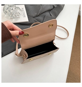 Close-up of the open interior with magnetic snap closures and gold hardware on a nude bag