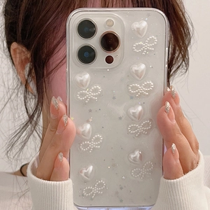 Coque iPhone à paillettes avec cœurs et nœuds en perles 3D tenue par un mannequin