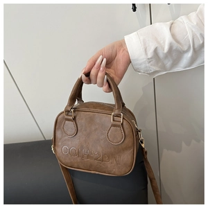 Detail of vintage brown leather Boston bag with embossed logo and metal strap buckle