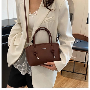 Détail d'un sac bandoulière en cuir marron vintage avec doubles poignées et lettrage mode