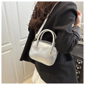 Detail of silver metallic mini handbag with cylinder handle and detachable shoulder strap