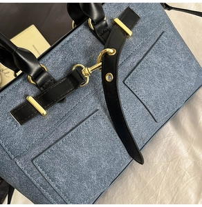 Detailed macro view of blue textured fabric with black leather trim and gold buckles