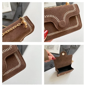 Detail view of brown suede crossbody bag with white arrow stitching and gold chain