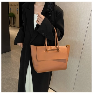 Close-up of a brown leather tote bag with flap closure and slender shoulder handles