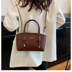 Détail du sac à main en cuir marron foncé avec lettrage fashion et nœud décoratif