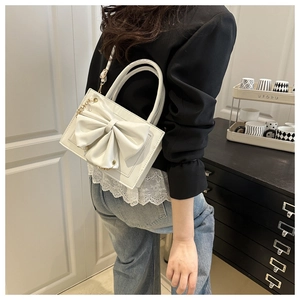 Petit sac blanc avec grand nœud porté par un mannequin dans un cadre intérieur élégant et chic