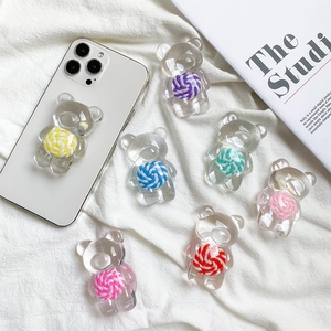 Gros plan de supports de téléphone ours colorés avec spirales sur tissu blanc