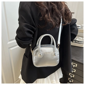 Close-up of a silver metallic crossbody bag with dual handles and FASHION lettering