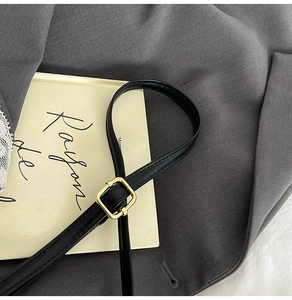 Detail of premium black leather shoulder strap with elegant gold rectangular metal buckle