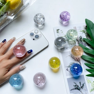 Colorful crystal ball phone grip with floating glitter and gold foil on white background