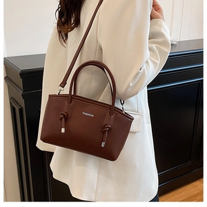 Détail d'un sac à main marron foncé avec imprimé mode et décoration de nœud tordu