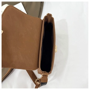 Top view of brown shoulder bag interior with black lining and golden metal hardware