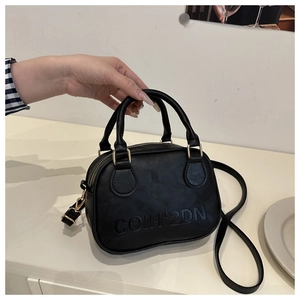 Close-up of black leather bag featuring embossed lettering and golden metal hardware