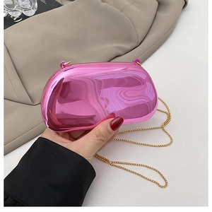 Gros plan d'une pochette en acrylique rose brillant avec détail de bandoulière dorée