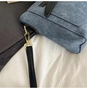 Detailed macro view of the blue textured crossbody bag featuring gold metal hardware