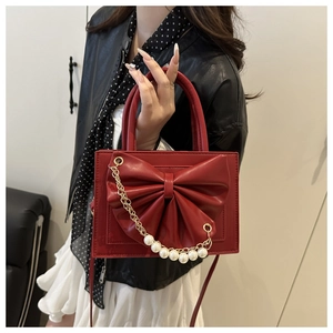 Détail d'un sac à main rouge carré avec grand nœud et élégantes perles décoratives