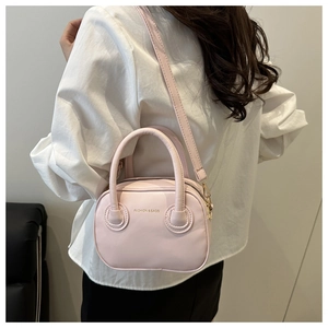 Detail of pink leather handbag with gold lettering and adjustable crossbody strap
