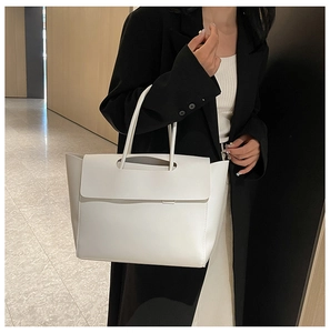 Dettaglio della borsa tote minimalista bianco avorio con manici sottili su modella