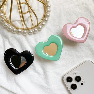 Close-up of heart-shaped phone grips in black, green, and pink with mini makeup mirrors