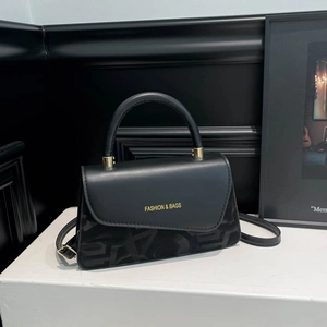 Minimalist black square crossbody bag with gold lettering and geometric texture