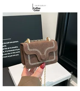 Detail of coffee brown crossbody bag with white wavy stitching and gold chain strap