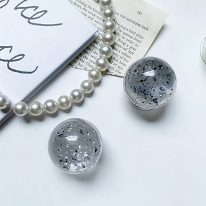Detailed macro view of clear crystal phone grips with silver foil inside on a white desk