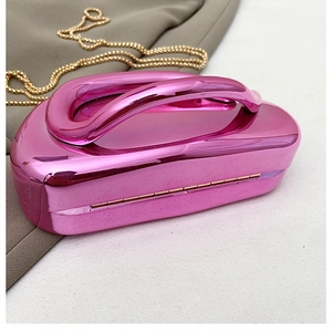 Détail de la pochette de soirée fuchsia avec poignée incurvée et bandoulière dorée