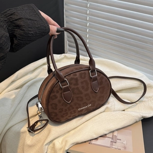 Brown leopard print oval crossbody bag with top handle on minimalist white fabric