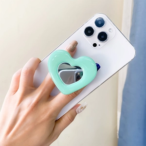 Detail of mint green heart-shaped phone grip with mirror shown on a white smartphone