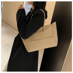 Large beige tote bag shown on model highlighting its spacious size and minimalist design